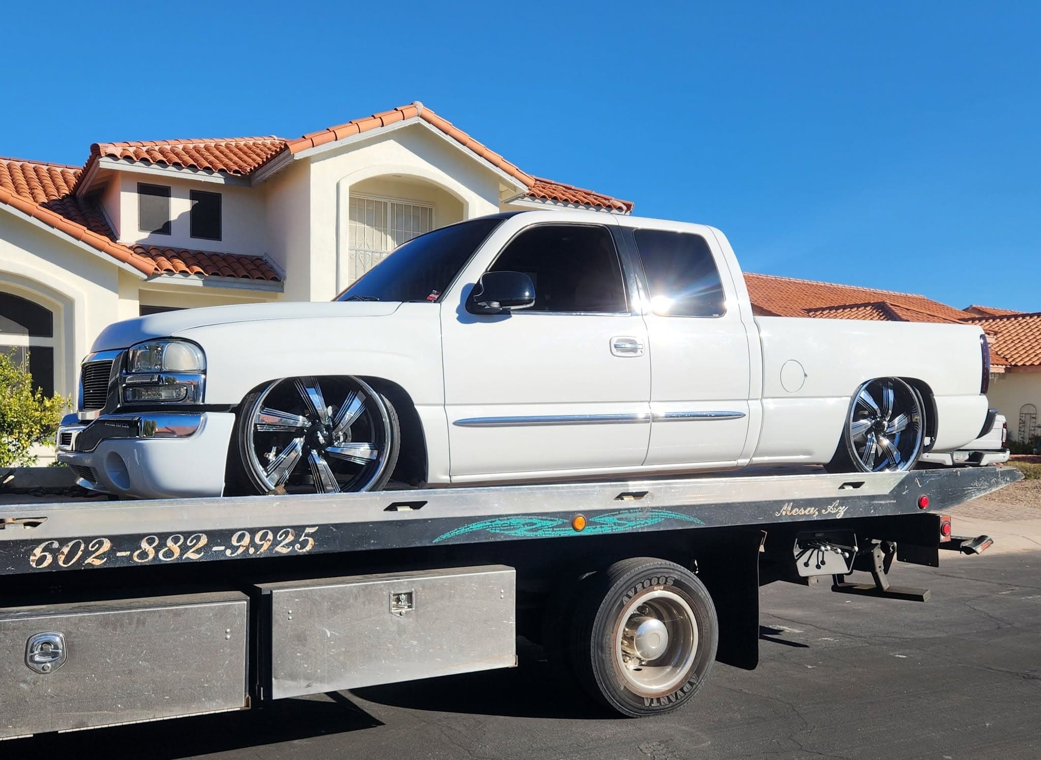 F&S Towing flatbed hauling a lowered white GMC Sierra pickup